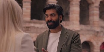 Movie still from “Love in the Villa” (2022), directed by Mark Steven Johnson – A man with long hair and a beard is smiling; Close Up shot, Over the shoulder angle