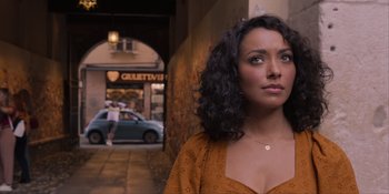 Movie still from “Love in the Villa” (2022), directed by Mark Steven Johnson – A woman standing in front of a building with a car in the background; Close Up shot, Over the shoulder angle