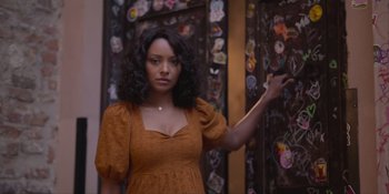 Movie still from “Love in the Villa” (2022), directed by Mark Steven Johnson – A woman in an orange dress standing in front of a wall; Close Up shot, Over the shoulder angle