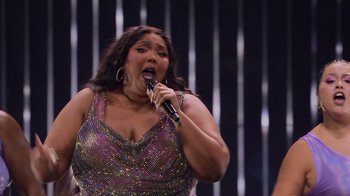 Movie still from “Love, Lizzo” (2022), directed by Doug Pray – A woman is singing into a microphone on a stage; Medium shot, Low angle