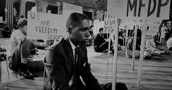 A black and white photo of a man sitting on the ground