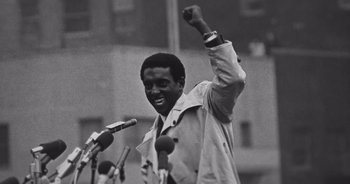 A black and white photo of a man raising his fist in the air