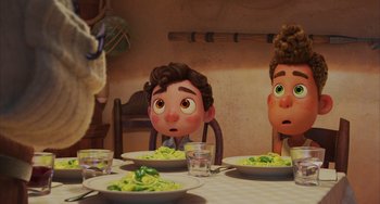 Movie still from “Luca” (2021), directed by Enrico Casarosa – A couple of people sitting at a table with plates of food; Close Up shot, Over the shoulder angle