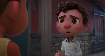 Movie still from “Luca” (2021), directed by Enrico Casarosa – A cartoon of a boy holding a book in front of a brick wall; Close Up shot, Over the shoulder angle