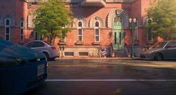 Movie still from “Luck” (2022), directed by Peggy Holmes – A person sitting on the side of the road near a building; Extreme Wide shot, High angle