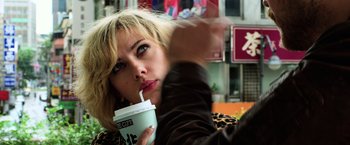 Movie still from “Lucy” (2014), directed by Luc Besson – A person holding a cup of coffee; Close Up shot, Over the shoulder angle