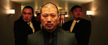 Movie still from “Lucy” (2014), directed by Luc Besson – A person wearing a suit and tie; Close Up shot, Low angle