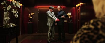 Movie still from “Lucy” (2014), directed by Luc Besson – Two men in suits and ties are playing a game; Medium shot, Low angle