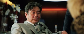 Movie still from “Lucy” (2014), directed by Luc Besson – A person wearing a suit and tie; Close Up shot, Low angle