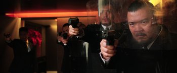 Movie still from “Lucy” (2014), directed by Luc Besson – A man holding a gun in front of a mirror; Medium shot, Low angle