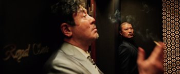 Movie still from “Lucy” (2014), directed by Luc Besson – A man smoking a cigarette in an elevator; Medium shot, Low angle
