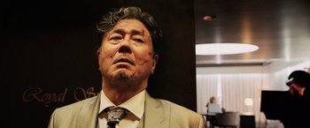 Movie still from “Lucy” (2014), directed by Luc Besson – An older man with a bloody nose is looking at the camera; Close Up shot, Low angle