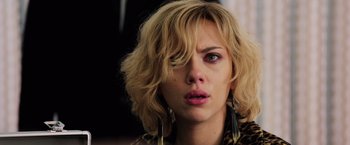 Movie still from “Lucy” (2014), directed by Luc Besson – A person wearing a jacket and earrings; Close Up shot, Low angle