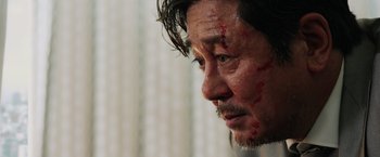 Movie still from “Lucy” (2014), directed by Luc Besson – A person with blood on his face; Close Up shot, Over the shoulder angle