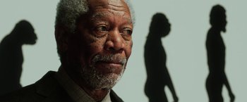 Movie still from “Lucy” (2014), directed by Luc Besson – An older man is looking at the camera with a shadow behind him on the wall; Close Up shot, Low angle