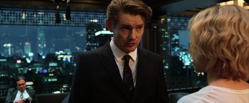 Movie still from “Lucy” (2014), directed by Luc Besson – A man wearing a suit and tie in front of a window; Close Up shot, Over the shoulder angle