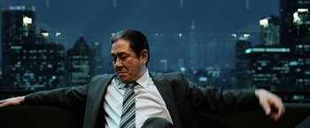 Movie still from “Lucy” (2014), directed by Luc Besson – A person wearing a suit and tie; Medium shot, Low angle