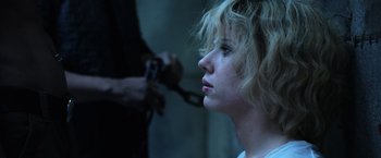 Movie still from “Lucy” (2014), directed by Luc Besson – A woman is chained to a wall and looking into the distance; Close Up shot, Over the shoulder angle
