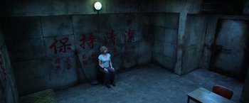 Movie still from “Lucy” (2014), directed by Luc Besson – A woman sitting on a chair in a room; Wide shot, High angle