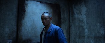 Movie still from “Lucy” (2014), directed by Luc Besson – A man in a blue shirt is looking at the camera; Medium shot, Low angle