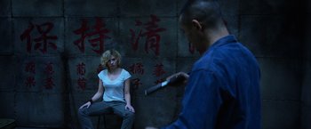 Movie still from “Lucy” (2014), directed by Luc Besson – A woman sitting on a chair in front of a man; Wide shot, Over the shoulder angle