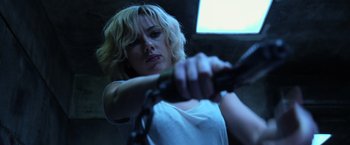 Movie still from “Lucy” (2014), directed by Luc Besson – A woman holding onto a metal chain while standing up; Close Up shot, Low angle