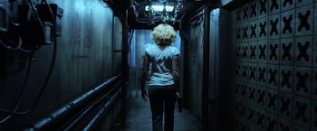 Movie still from “Lucy” (2014), directed by Luc Besson – A woman walking down a hallway in a building; Wide shot, Low angle