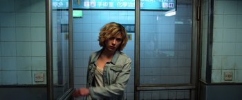 Movie still from “Lucy” (2014), directed by Luc Besson – A woman standing in front of a wall; Medium shot, Low angle