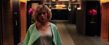 Movie still from “Lucy” (2014), directed by Luc Besson – A woman standing in a hallway with a green jacket on; Close Up shot, Low angle