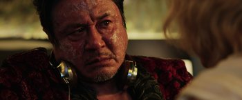 Movie still from “Lucy” (2014), directed by Luc Besson – A person wearing headphones on a couch; Close Up shot, Low angle