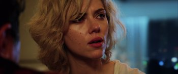 Movie still from “Lucy” (2014), directed by Luc Besson – A person with curly blonde hair; Close Up shot, Over the shoulder angle