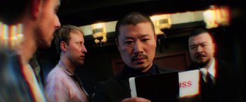 Movie still from “Lucy” (2014), directed by Luc Besson – A man in a suit and tie looking at a tablet computer; Close Up shot, Low angle