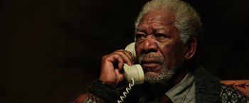 Movie still from “Lucy” (2014), directed by Luc Besson – An older man talking on a phone while wearing a tie; Close Up shot, Low angle