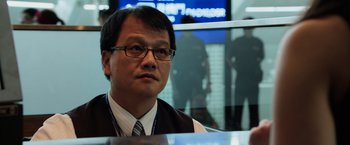 Movie still from “Lucy” (2014), directed by Luc Besson – A man wearing glasses and a vest sitting in front of a window; Close Up shot, Over the shoulder angle