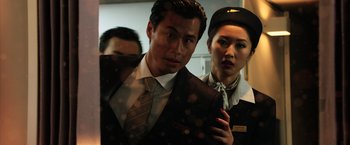 Movie still from “Lucy” (2014), directed by Luc Besson – A man and a woman in a suit and tie standing next to each other; Close Up shot, Low angle