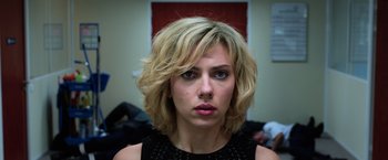 Movie still from “Lucy” (2014), directed by Luc Besson – A person with short blonde hair; Close Up shot, Over the shoulder angle