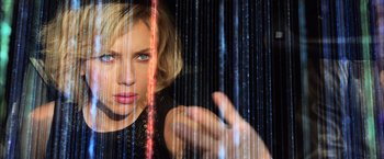 Movie still from “Lucy” (2014), directed by Luc Besson – A woman in a black dress looking at the camera; Close Up shot, Overhead angle
