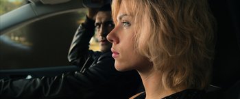 Movie still from “Lucy” (2014), directed by Luc Besson – A man and a woman in a car looking out the window; Close Up shot, Low angle