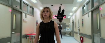 Movie still from “Lucy” (2014), directed by Luc Besson – A woman in a black dress standing next to a man in a black suit; Medium shot, Low angle