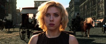 Movie still from “Lucy” (2014), directed by Luc Besson – A person with short blonde hair; Close Up shot, Over the shoulder angle