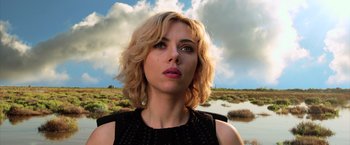 Movie still from “Lucy” (2014), directed by Luc Besson – A person wearing a black shirt near a body of water; Close Up shot, Low angle