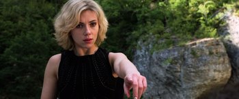 Movie still from “Lucy” (2014), directed by Luc Besson – A woman in a black dress pointing to the side; Close Up shot, Low angle
