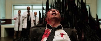 Movie still from “Lucy” (2014), directed by Luc Besson – A man with blood all over his face and neck; Medium shot, Low angle