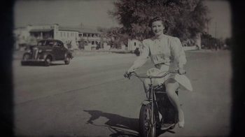 Movie still from “Lucy and Desi” (2022), directed by Amy Poehler – An old black and white photo of a woman riding a bike; Wide shot, High angle
