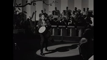 Movie still from “Lucy and Desi” (2022), directed by Amy Poehler – A black and white photo of a man holding a frisbee; Wide shot, High angle