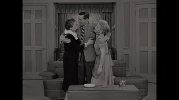 Movie still from “Lucy and Desi” (2022), directed by Amy Poehler – Two women and a man are hugging in a living room; Wide shot, High angle
