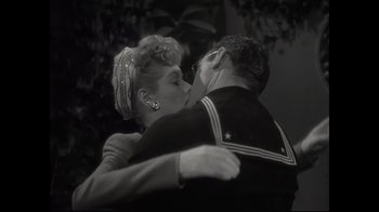 Movie still from “Lucy and Desi” (2022), directed by Amy Poehler – A man and a woman kissing each other in front of trees; Close Up shot, High angle