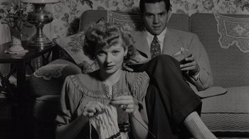 Movie still from “Lucy and Desi” (2022), directed by Amy Poehler – A man and a woman sitting on a couch knitting; Medium shot, High angle