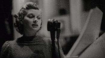 Movie still from “Lucy and Desi” (2022), directed by Amy Poehler – A black and white photo of a woman holding a hair dryer; Close Up shot, Low angle
