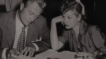 Movie still from “Lucy and Desi” (2022), directed by Amy Poehler – A man and a woman sitting next to each other at a table; Close Up shot, High angle